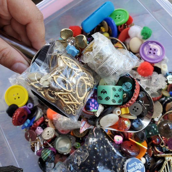 Picture of Metal Scoop & hand with trinkets example in scoops bucket